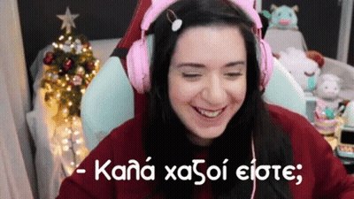 A Woman Wearing Pink Headphones Is Sitting In Front Of A Christmas Tree And Smiling . GIF