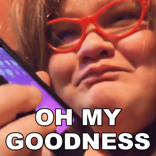 A Woman Wearing Red Glasses Is Holding A Cell Phone With The Words Oh My Goodness Above Her GIF