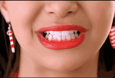 A Woman Wearing Red Lipstick And Candy Cane Earrings GIF