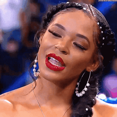 A Woman Wearing Red Lipstick And Hoop Earrings Is Making A Funny Face . GIF