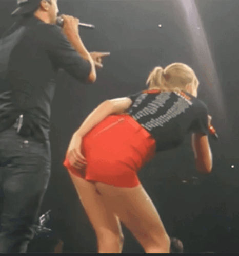 A Woman Wearing Red Shorts And A Black Shirt That Says Taylor Swift GIF