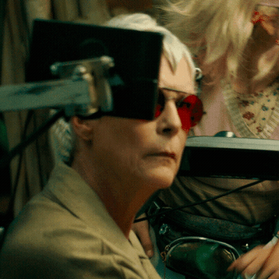A Woman Wearing Red Sunglasses Is Looking At A Monitor GIF