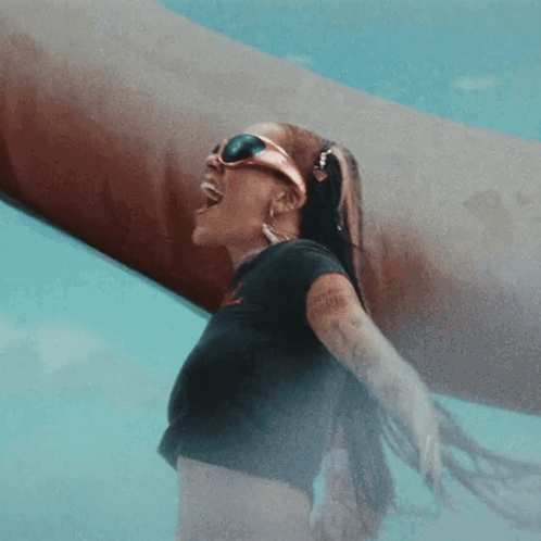 A Woman Wearing Sunglasses And A Black Shirt Stands In A Pool GIF