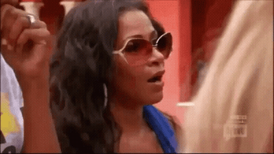 A Woman Wearing Sunglasses And A Blue Shirt Is Talking To A Man . GIF