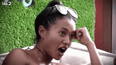 A Woman Wearing Sunglasses And A Choker Is Sitting On A Couch . GIF