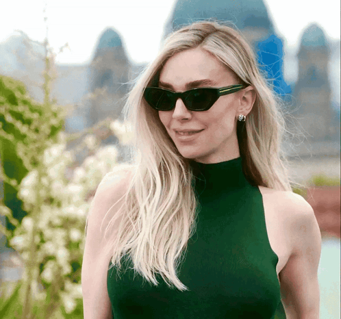 A Woman Wearing Sunglasses And A Green Turtleneck GIF