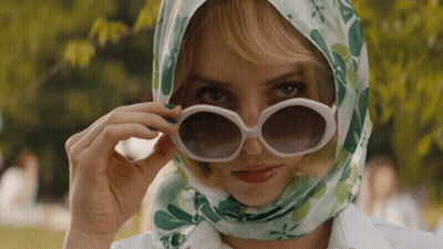 A Woman Wearing Sunglasses And A Head Scarf Looks At The Camera GIF