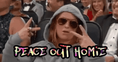 A Woman Wearing Sunglasses And A Hoodie Is Sitting In A Crowd Of People And Making A Peace Sign .. GIF