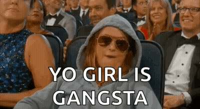 A Woman Wearing Sunglasses And A Hoodie Is Sitting In A Crowd Of People And Says `` Yo Girl Is Gangsta '' . GIF
