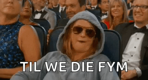 A Woman Wearing Sunglasses And A Hoodie Is Sitting In A Crowd Of People With The Words Til We Die Fym Behind Her . GIF