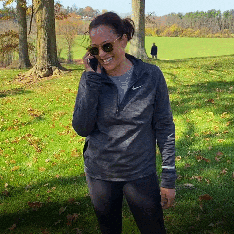 A Woman Wearing Sunglasses And A Nike Shirt Is Talking On Her Cell Phone GIF