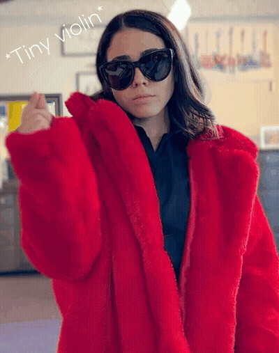 A Woman Wearing Sunglasses And A Red Fur Coat With The Words " Tiny Violin " Below Her GIF