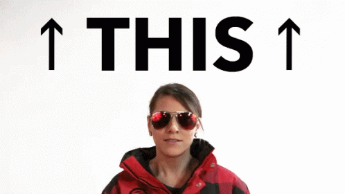 A Woman Wearing Sunglasses And A Red Jacket Is Pointing Up With The Words " This " Above Her GIF