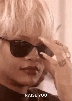 A Woman Wearing Sunglasses And A Ring Is Holding Her Hand To Her Forehead . GIF