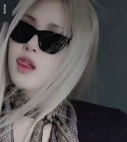 A Woman Wearing Sunglasses And A Scarf Has The Word Mora On The Bottom Right GIF