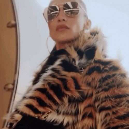A Woman Wearing Sunglasses And A Tiger Print Fur Coat . GIF