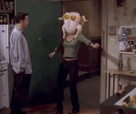 A Woman Wearing Sunglasses And A Turkey Head Stands In A Kitchen GIF