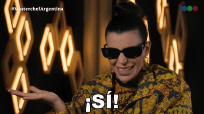 A Woman Wearing Sunglasses And A Yellow And Black Jacket Says " Si " GIF