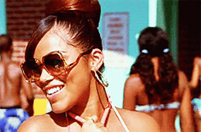 A Woman Wearing Sunglasses And Earrings Is Smiling GIF