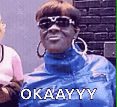 A Woman Wearing Sunglasses And Hoop Earrings Is Making A Funny Face And Saying Okay . GIF