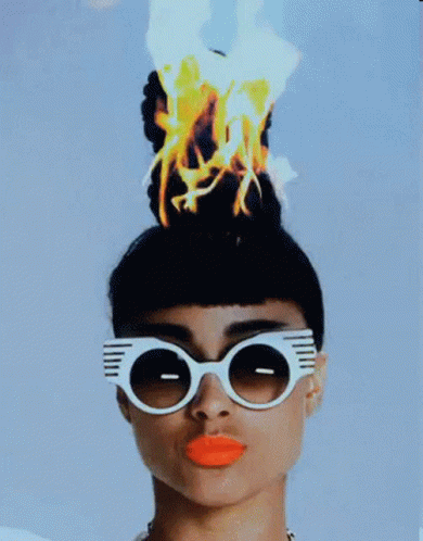 A Woman Wearing Sunglasses Has A Bunch Of Fire On Her Head GIF