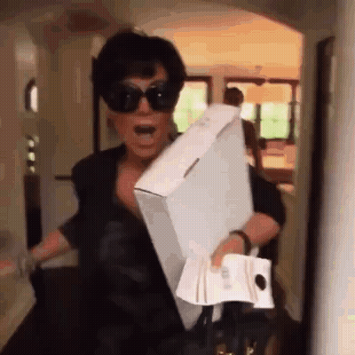 A Woman Wearing Sunglasses Is Carrying A Large Box And A Bag . GIF