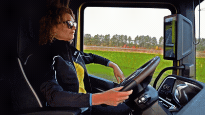 A Woman Wearing Sunglasses Is Driving A Truck With A Steering Wheel That Says Volvo On It GIF