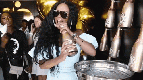 A Woman Wearing Sunglasses Is Holding A Bottle Of Champagne In Her Hand . GIF