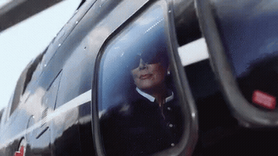 A Woman Wearing Sunglasses Is Looking Out Of A Helicopter Window . GIF
