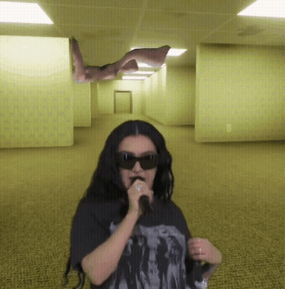 A Woman Wearing Sunglasses Is Singing Into A Microphone In A Hallway GIF