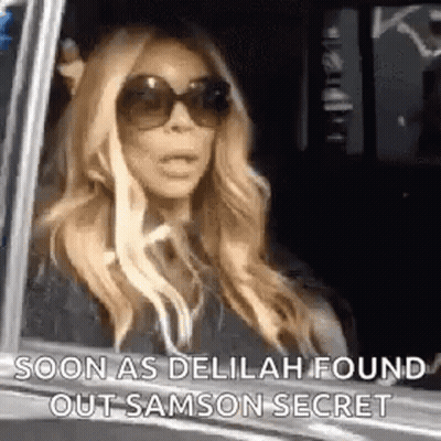 A Woman Wearing Sunglasses Is Sitting In A Car And Looking Out The Window . GIF