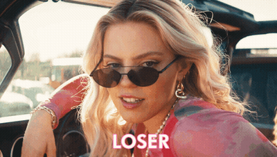 A Woman Wearing Sunglasses Is Sitting In A Car With The Word Loser Written On The Side GIF