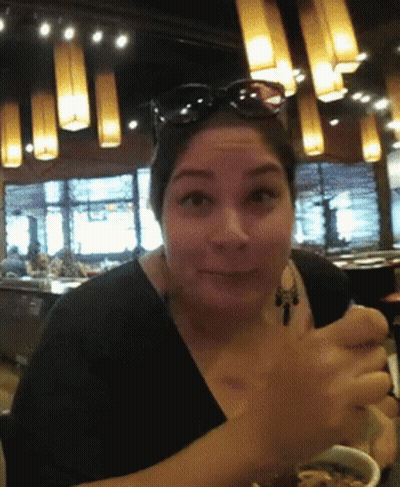 A Woman Wearing Sunglasses Is Sitting In A Restaurant GIF
