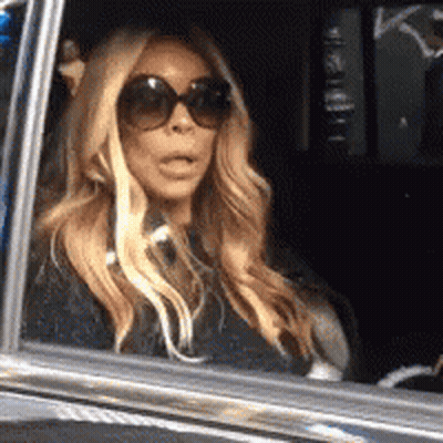 A Woman Wearing Sunglasses Is Sitting In The Back Seat Of A Car . GIF