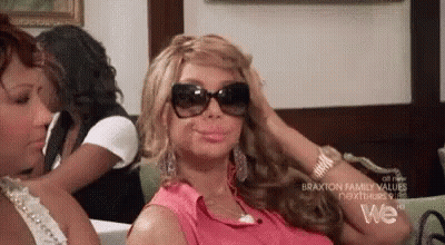 A Woman Wearing Sunglasses Is Sitting On A Couch . GIF
