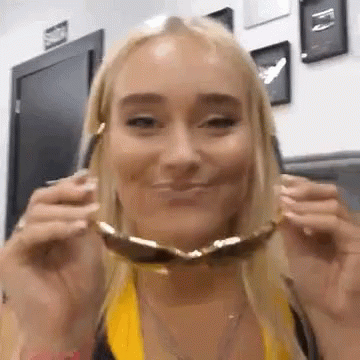 A Woman Wearing Sunglasses Is Smiling And Making A Face . GIF