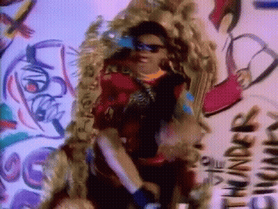 A Woman Wearing Sunglasses Is Standing In Front Of A Wall That Says Thunder GIF