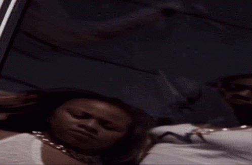 A Woman Wearing Sunglasses Looks At Her Reflection In A Window GIF