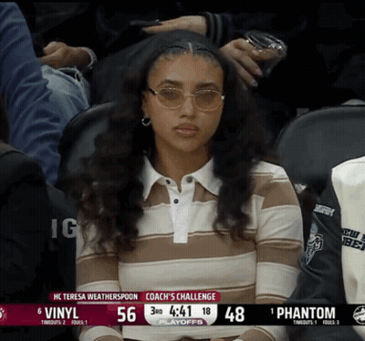 A Woman Wearing Sunglasses Sits In The Stands Watching A Basketball Game GIF