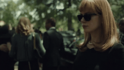 A Woman Wearing Sunglasses Stands In A Crowded Area GIF