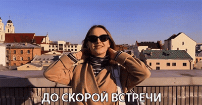 A Woman Wearing Sunglasses Stands In Front Of A City With The Words " До Скорой Встречи " Written Below Her GIF