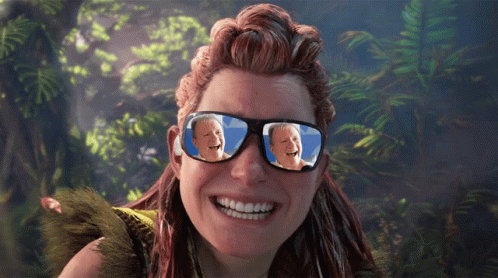 A Woman Wearing Sunglasses With A Picture Of A Man Laughing In The Reflection GIF