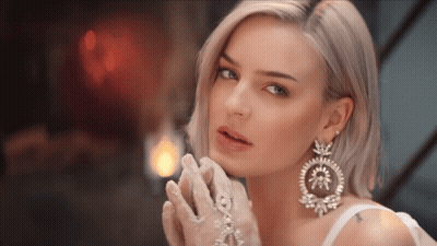 A Woman Wearing White Gloves And Large Earrings GIF