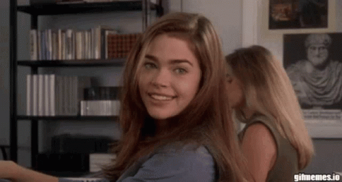 A Woman Whispering Into Another Woman 'S Ear With Gifmemes.io Written On The Bottom GIF