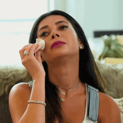 A Woman Wipes Her Face With A Tissue While Wearing Ace Necklace GIF