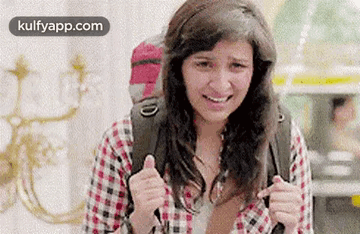 A Woman With A Backpack Is Smiling And Giving A Thumbs Up Sign . GIF