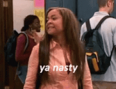A Woman With A Backpack Is Standing In A Hallway And Says Ya Nasty . GIF