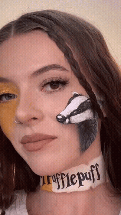 A Woman With A Badger Painted On Her Face And A Choker That Says ' Rufflepuff ' On It GIF