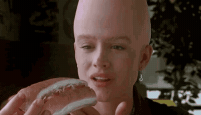 A Woman With A Bald Head Is Holding A Hot Dog . GIF