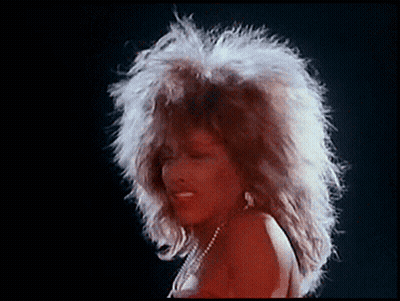 A Woman With A Big Afro Is Wearing A Red Dress And Pearls GIF